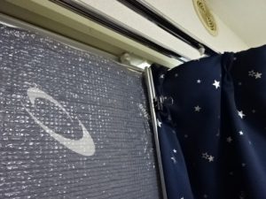 カーテンをエアコンの外枠に固定して隙間を塞ぐ。